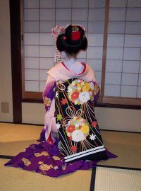 Rear view of a maiko in a teahouse, her richly embroidered obi clearly visible
