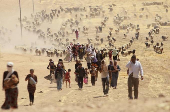 Displaced people from the minority Yazidi sect, fleeing violence from forces loyal to the Islamic State in Sinjar town, walk towards the Syrian border, on the outskirts of Sinjar mountain.