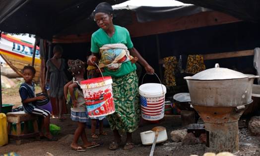 A woman carries buckets at the fishing port of Conakry, Guinea, in November 2014. A new study finds womens contribution to health and wellbeing of families and communities is undervalued worldwide.