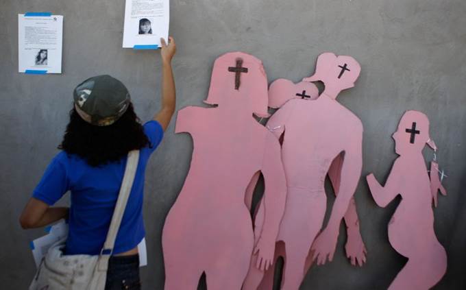 A woman posts a flyer with information about missing women next to cardboard figures after a rally led by Mexican poet Javier Sicilia to support victims of feminicides, in Ciudad Juarez June 10, 2011. Hundreds of Mexicans began a week-long procession through Mexico on Saturday to protest the country's bloody drug war, led by Sicilia, a crusading poet whose son was murdered by suspected cartel hitmen. Human rights activists and families of victims of violence formed a peace caravan and piled into 13 buses and more than two dozen cars to set out on a 12-state tour that will end in Ciudad Juarez, Mexico's most violent drug war city on the U.S. border. 